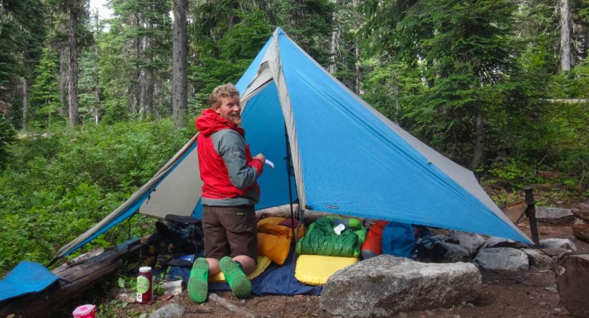 a person smiles as they set up a shelter for the night